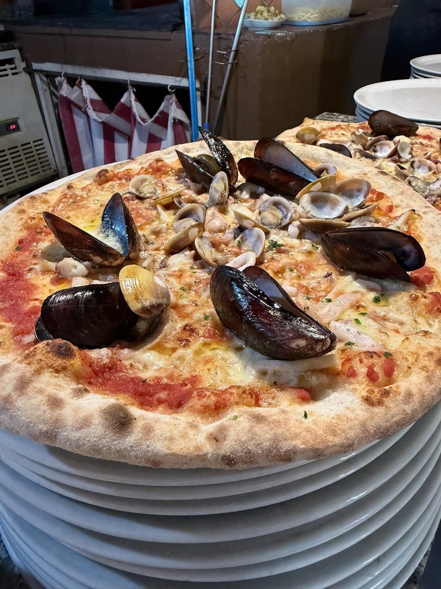 Pizza ai frutti di mare con cozze e vongole cotta nel forno a legna del Ristorante La Mesenda a San Teodoro